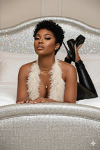 Woman in a luxurious setting with a sparkly headboard and black high-heeled shoes.