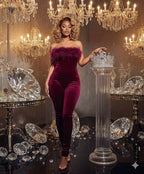 Woman in a burgundy jumpsuit with feather details standing in an opulent room with chandeliers and diamonds.