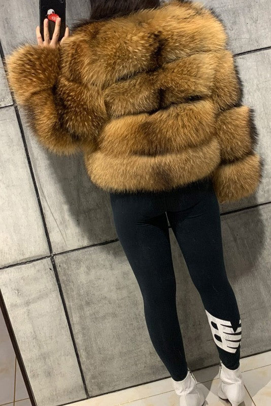 Person wearing a brown fur coat and black pants with white accents on a tiled floor.