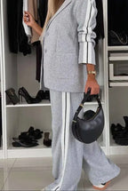 Person wearing a gray outfit with white stripes holding a black handbag in a room with shelves of shoes.