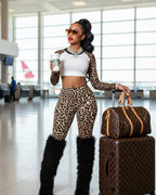 Woman in leopard print outfit with a suitcase and Starbucks cup in an airport.