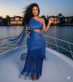 Woman in a blue fringe dress holding a glass of wine on a boat at sunset.