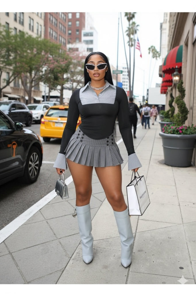 Woman in a black and gray outfit with knee-high boots walking on a city street.