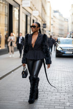 Woman in a black outfit with leather elements walking on a city street.