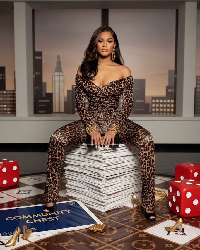 Woman in leopard print outfit sitting on a stack of cards with dice and a board game in the background