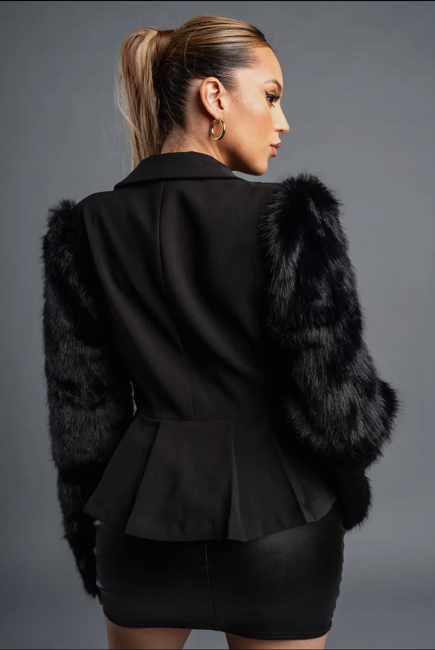 Black peplum jacket with fur trim worn by a person on a gray background