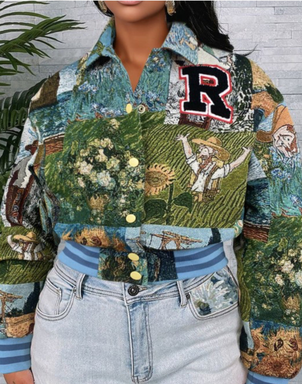 Person wearing a patchwork jacket with a 'R' logo, standing against a gray wall with greenery.