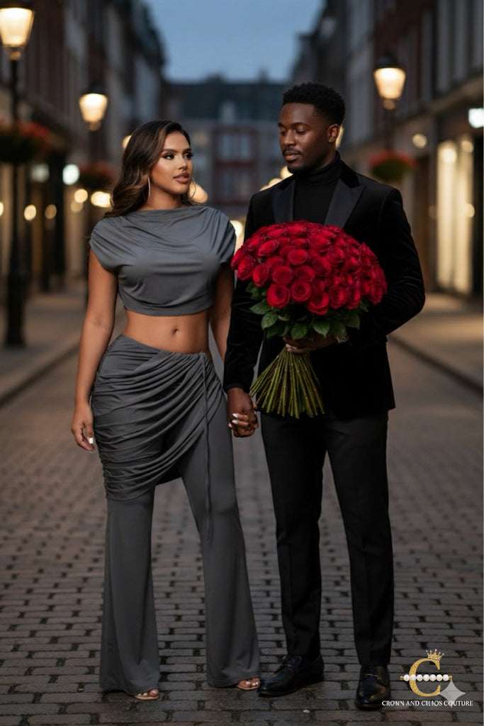Man in a suit holding red roses and a woman in gray outfit on a street at night.