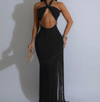 Black evening gown with open back and sheer side panels on a plain background