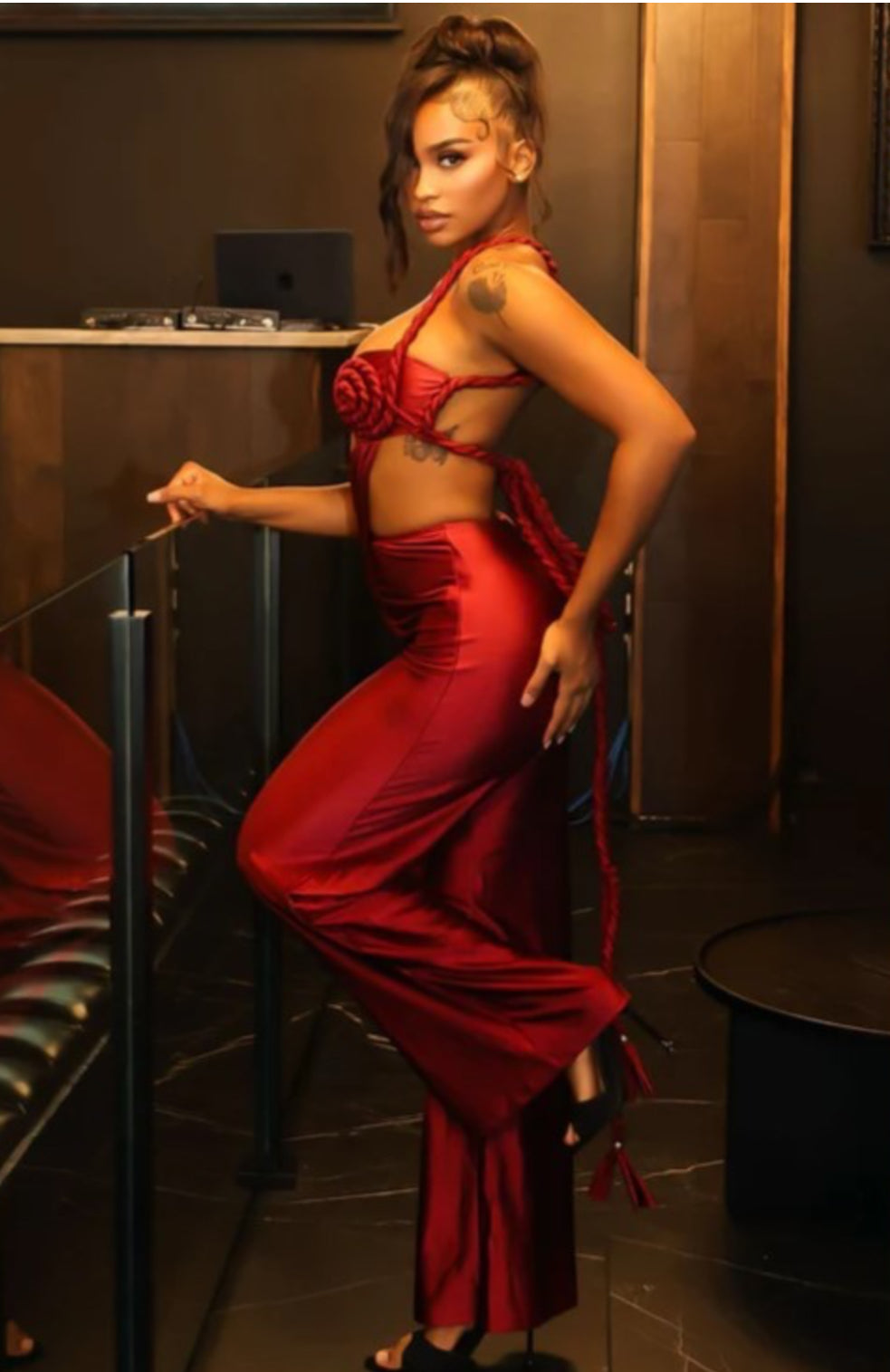 Woman in a red outfit posing in a dimly lit room.