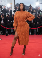 Woman in an orange cable knit dress on a red carpet with photographers in the background