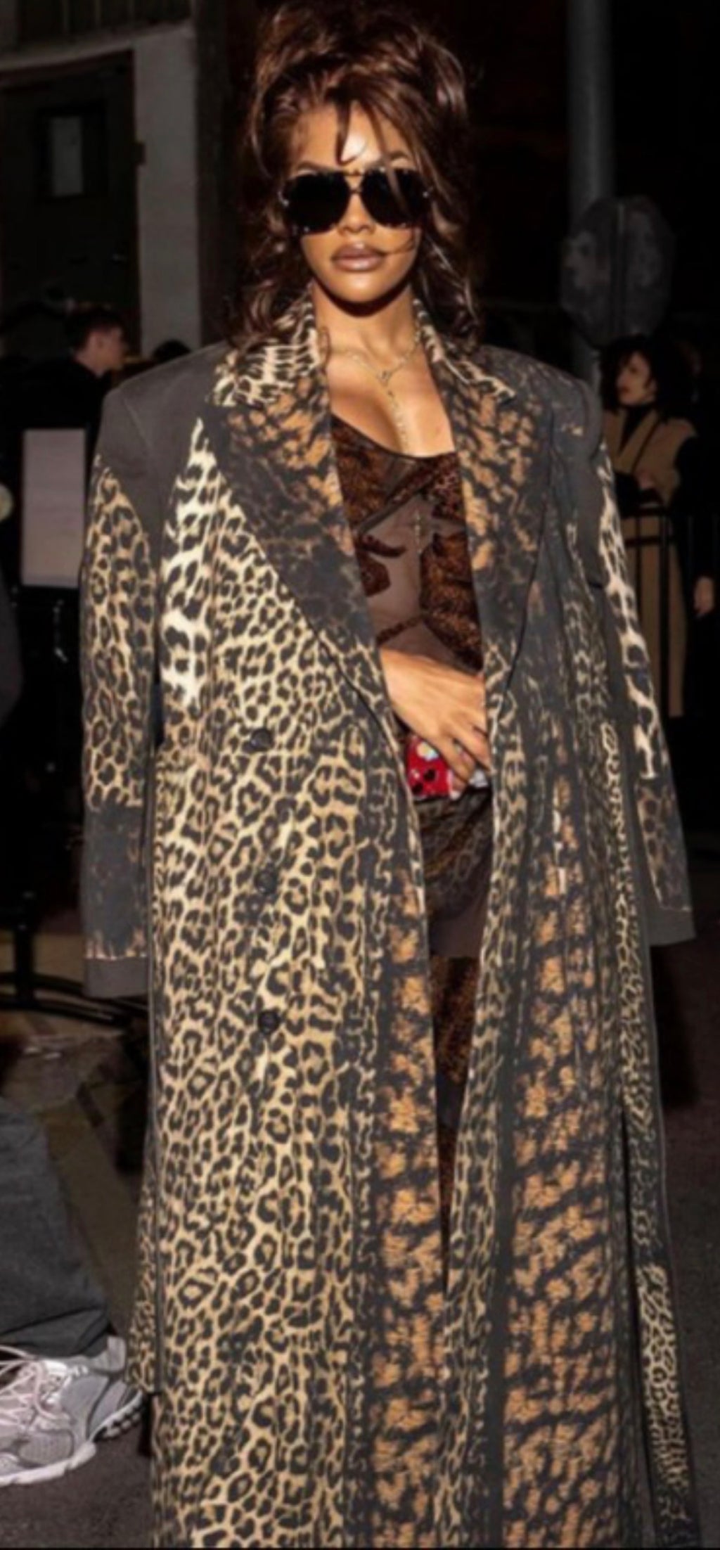 Person wearing a leopard print coat and sunglasses in an indoor setting