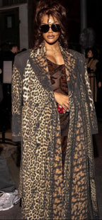 Person wearing a leopard print coat and sunglasses in an indoor setting
