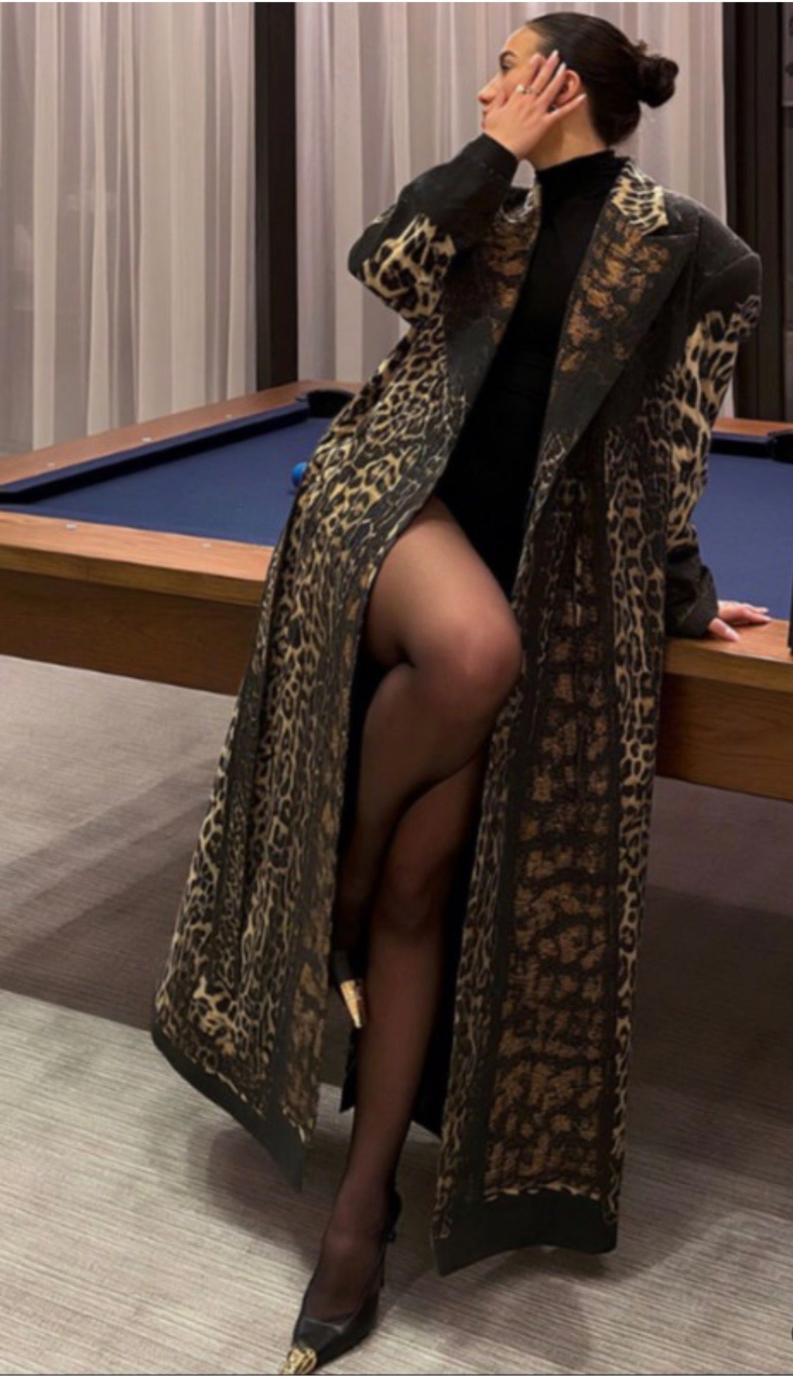Person wearing a leopard print coat in an indoor setting