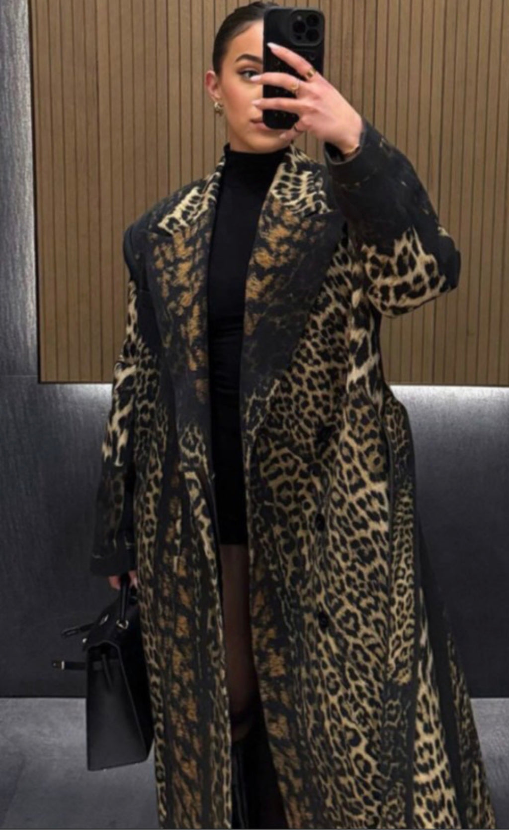 Person wearing a leopard print coat taking a mirror selfie.