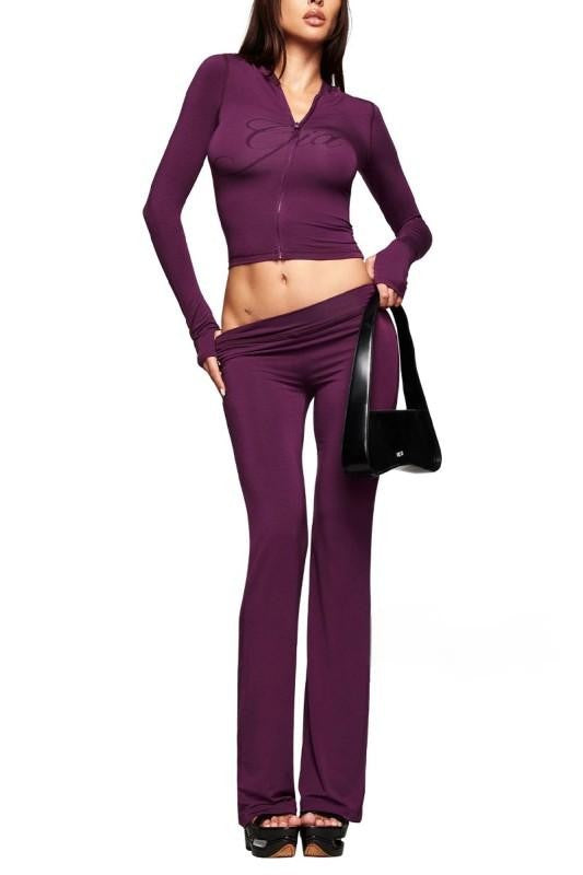 Woman wearing a purple outfit with a black handbag on a white background