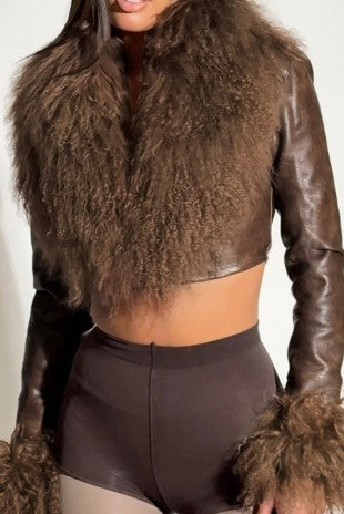 Person wearing a brown leather outfit with fur details on a plain background