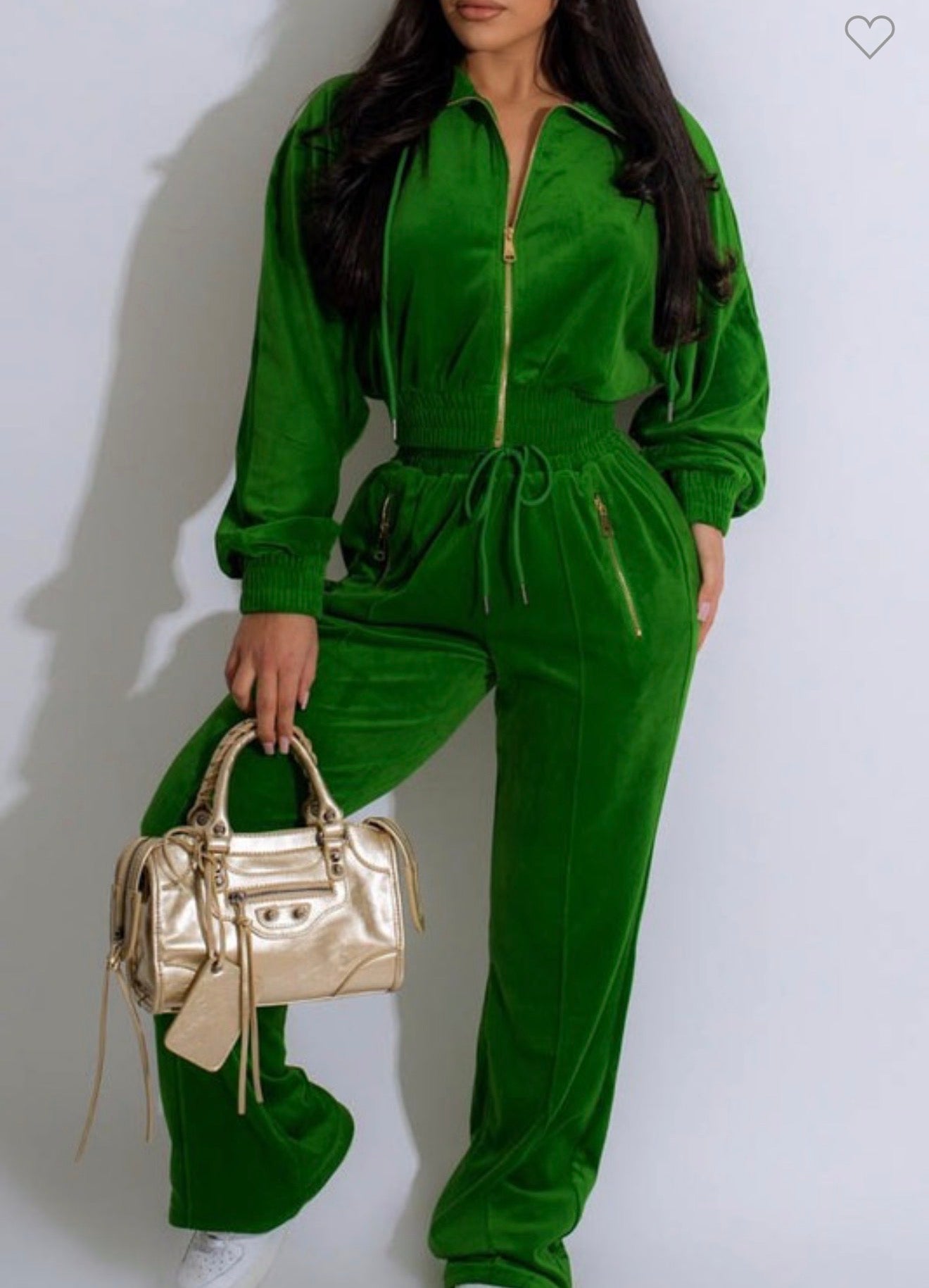 Person wearing a green tracksuit holding a gold handbag on a white background