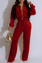 Person wearing a red jumpsuit holding a gold handbag against a white background
