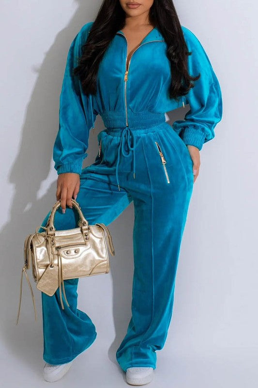 Woman wearing a blue tracksuit holding a gold handbag on a white background