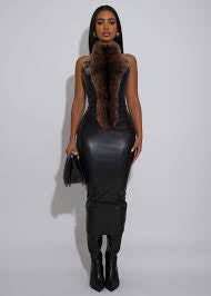 Woman wearing a black leather dress with fur trim against a white background