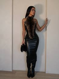 Woman in a black dress standing against a white wall